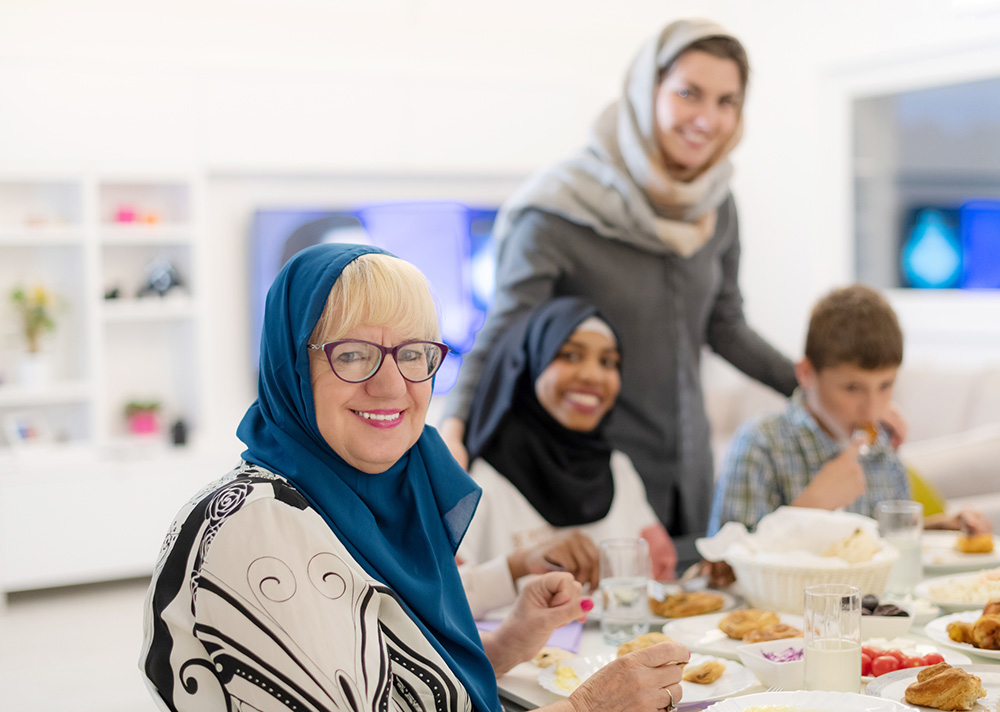 Smiling older woman with diabetes sitting down to a healthy dinner with her family